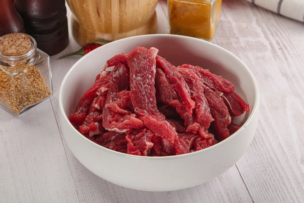 a bowl of beef cut into thin strips, which is the first step to making beef jerky