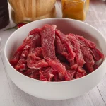 a bowl of beef cut into thin strips, which is the first step to making beef jerky