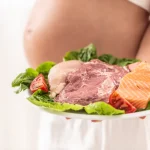 A pregnant woman holding a plate of raw meat and seafood while wondering to herself, can you eat beef jerky while pregnant?