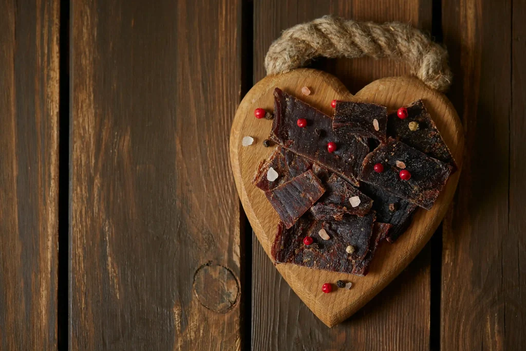 A wooden heart with beef jerky illustrating an answer to the question "is beef jerky healthy?"